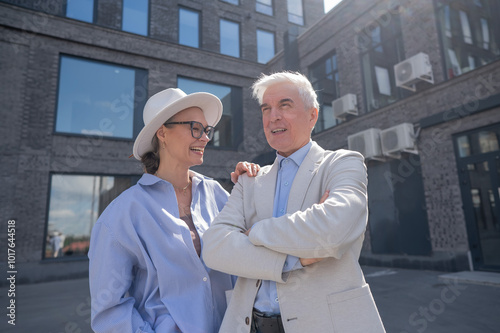 An elderly couple in love walks through the city. Portrait of a stylish gray-haired man and woman.  photo