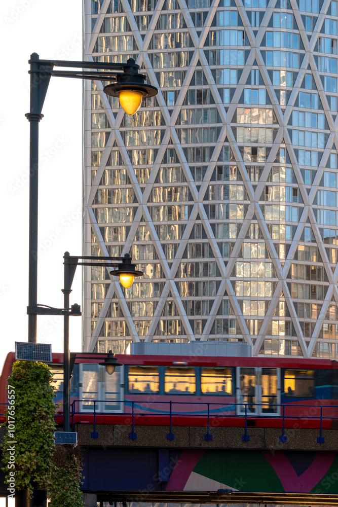 A brightly colored train rushes by in front of a modern building with a striking geometric design, showcasing urban life at its dynamic and bustling best. A brightly colored train rushes by in front of a modern building with a striking geometric design, showcasing urban life at its dynamic and bustling best.