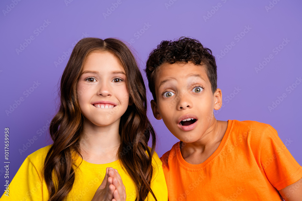 Photo of two impressed small kids open mouth wear t-shirt isolated on violet color background Photo of two impressed small kids open mouth wear t-shirt isolated on violet color background