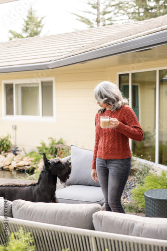 Woman holding a cup of coffee looking at her dog photo