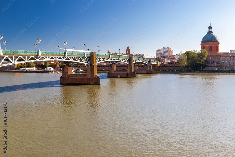 Obraz premium Golden sunset over Garonne river with views on the the pedestrian Saint-Pierre bridge, Place Saint-Pierre and the Grave hospital seen from the riverside 