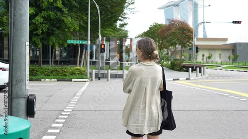 A girl is standing at a pedestrian crossing in Singapore