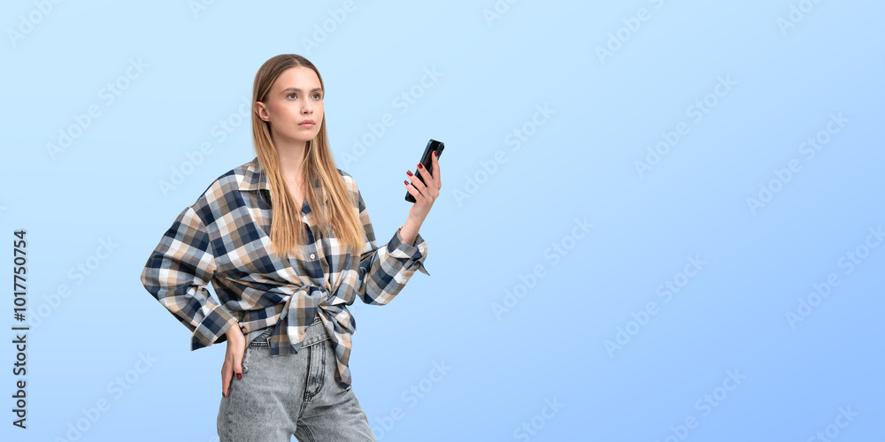 Pensive young woman with phone in hand, empty blue background Pensive young woman with phone in hand, empty blue background