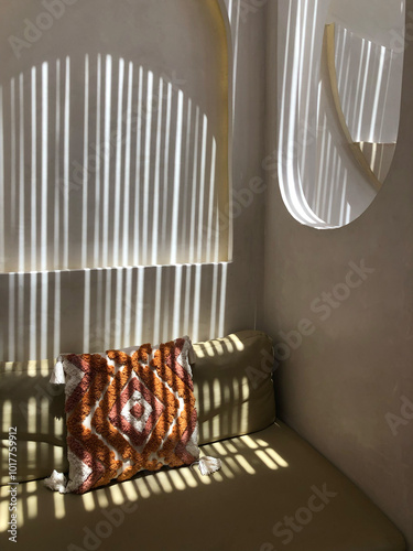 Minimalist room with geometric light patterns and decorative cushion
