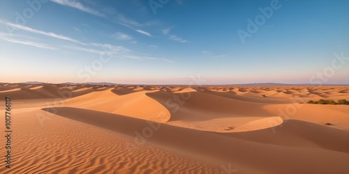 A vast desert landscape with rolling sand dunes under a clear blue sky
