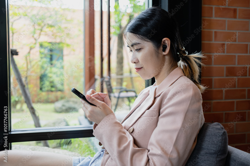 Young woman smiling and texting on smartphone while sitting in a coffee shop Young woman smiling and texting on smartphone while sitting in a coffee shop