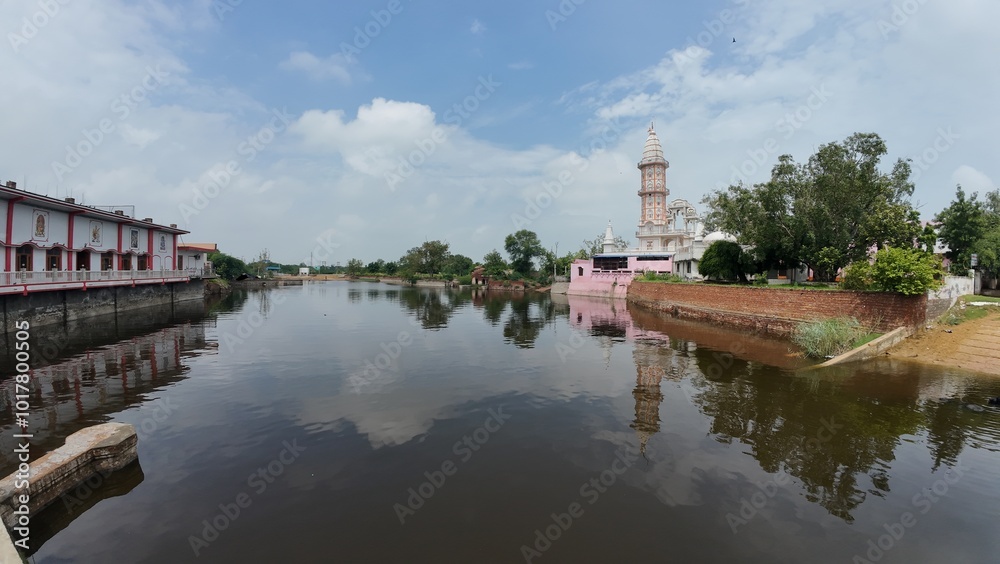 Tranquil pond in a village, showcasing a temple complex, embodying calmness and serving as a sacred pilgrimage destination. Haryana, India Tranquil pond in a village, showcasing a temple complex, embodying calmness and serving as a sacred pilgrimage destination. Haryana, India