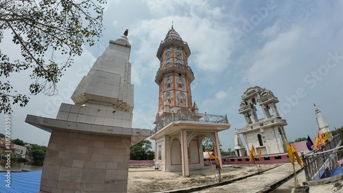  Exterior view of a Hindu temple with a towering structure against a backdrop of clouds and a clear sky