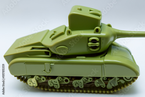 Tank with toy in gray on the . vehicle transport world concept. a small child's toy on a gray . a small girl is playing with a tank with green and gray lifestyle walls.