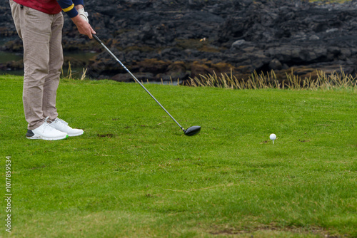 Golfer preparing to tee off near rocky coastline