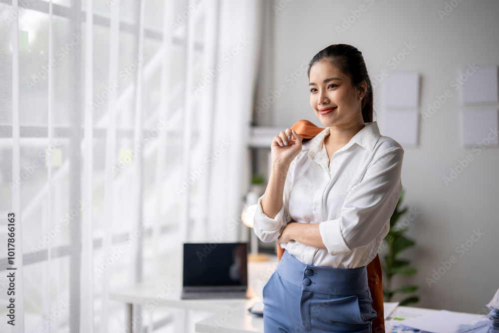 Young asian businesswoman smiling and looking through office window Young asian businesswoman smiling and looking through office window