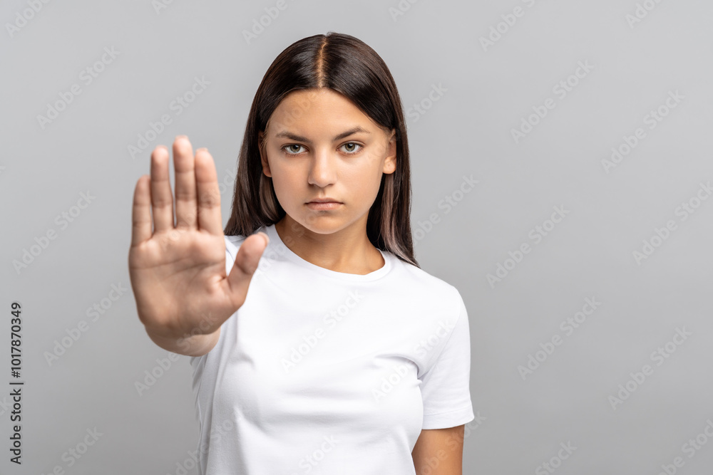 Serious teen girl holds hand forward in firm stop gesture, reject fear, discrimination, abuse. Girl power, strength in battling social pressures, depression. Schoolgirl independence and protection Serious teen girl holds hand forward in firm stop gesture, reject fear, discrimination, abuse. Girl power, strength in battling social pressures, depression. Schoolgirl independence and protection
