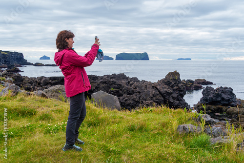 Woman photographing coastal landscape on Heimaey Island photo