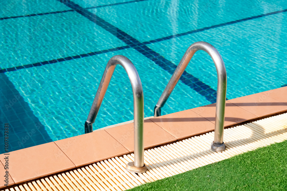 Swimming pool with stair ladder in the blue clear water. Poolside with handrail Stainless steel ladder in pool. Swimming pool with stair ladder in the blue clear water. Poolside with handrail Stainless steel ladder in pool.