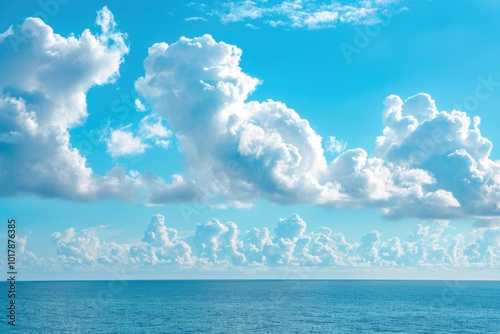 Blue sky with white fluffy clouds over calm ocean.