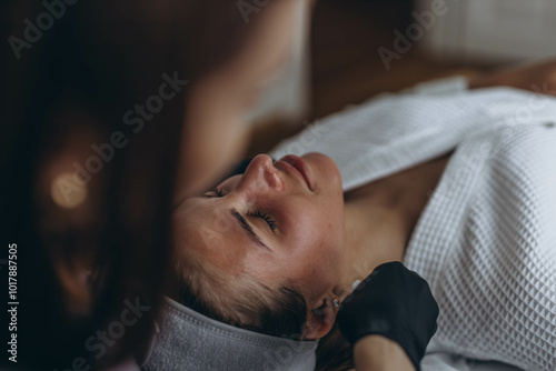 A beautiful woman enjoys a facial massage at a spa salon,indulging in skin and body care treatments.