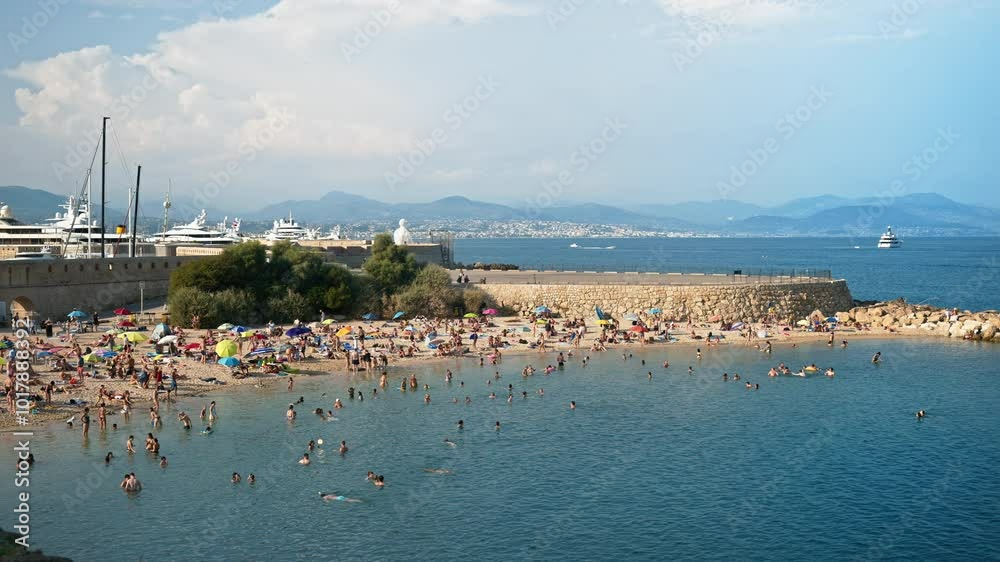 People swimming in the sea and relaxing on the beach in Antibes, France People swimming in the sea and relaxing on the beach in Antibes, France