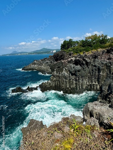 Scenic coastal landscape with rocky cliffs and clear blue ocean under a bright sky.