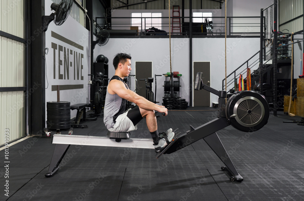 An athletic man in sportswear is engaged in an intense workout session on a rowing machine inside a well-equipped gym. An athletic man in sportswear is engaged in an intense workout session on a rowing machine inside a well-equipped gym.