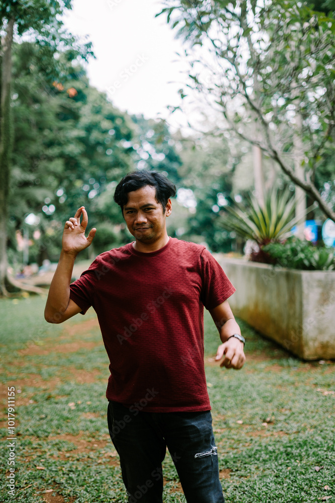 Obraz premium Southeast Asian man making an 'OK' gesture with his fingers, symbolizing approval or agreement