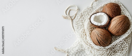Freshly harvested coconuts in a netted bag on a clean, white background