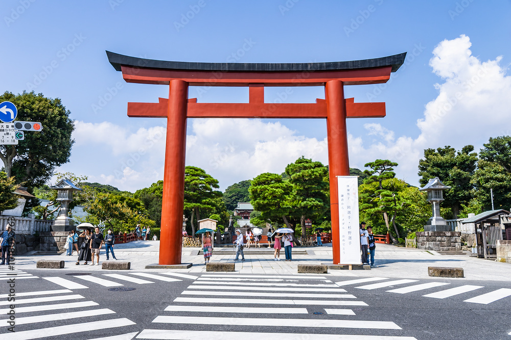 Obraz premium Giant Torii Gate at Street Entrance of Tsurugaoka Hachimangu Shrine, with Pedestrian Crosswalk and Visitors in Summer (Kamakura, Japan – August 2024)