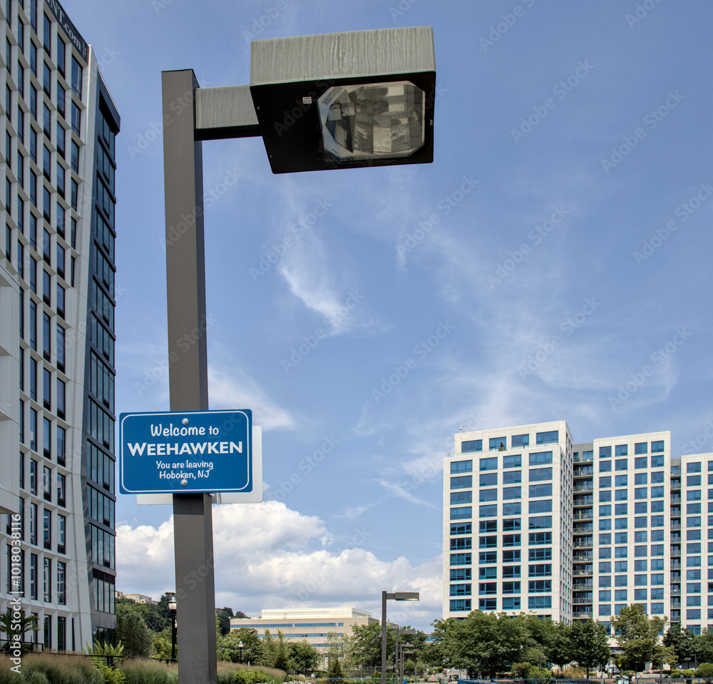 Welcome to Weehawken You are leaving Hoboken, NJ sign in front of modern high rise residential tower buildings on the Weehawken, New Jersey waterfront. Welcome to Weehawken You are leaving Hoboken, NJ sign in front of modern high rise residential tower buildings on the Weehawken, New Jersey waterfront.