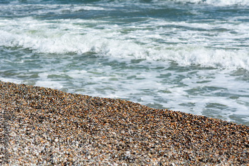 A pebble beach with gentle waves lapping the shore, creating a tranquil coastal scene. Mamaia beach, Constanta, Romania