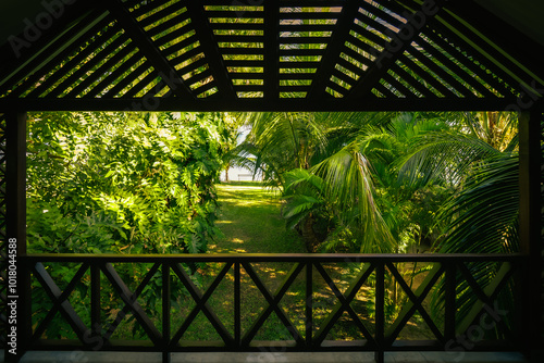 Beautiful view of an exotic tropical garden with lush foliage by the sea, seen from an elevated wooden porch, Grand Baie, Mauritius photo