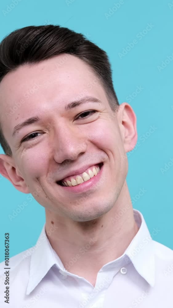Portrait of a young adult Caucasian friendly and excited man, looking and smiling at camera on blue background. Positive gentleman. Vertical video. Portrait of a young adult Caucasian friendly and excited man, looking and smiling at camera on blue background. Positive gentleman. Vertical video.
