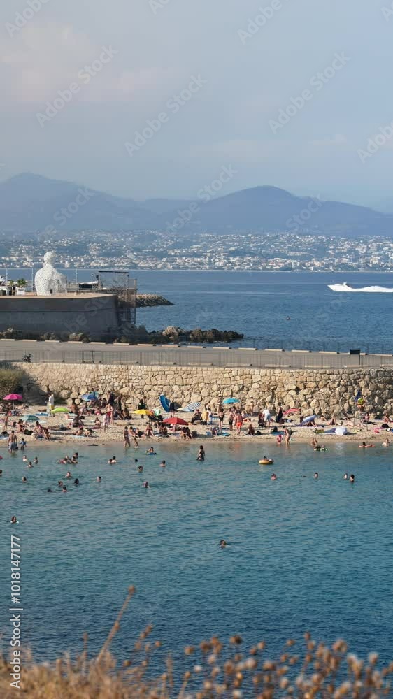 People swimming in the sea and relaxing on the beach in Antibes, France. Vertical People swimming in the sea and relaxing on the beach in Antibes, France. Vertical