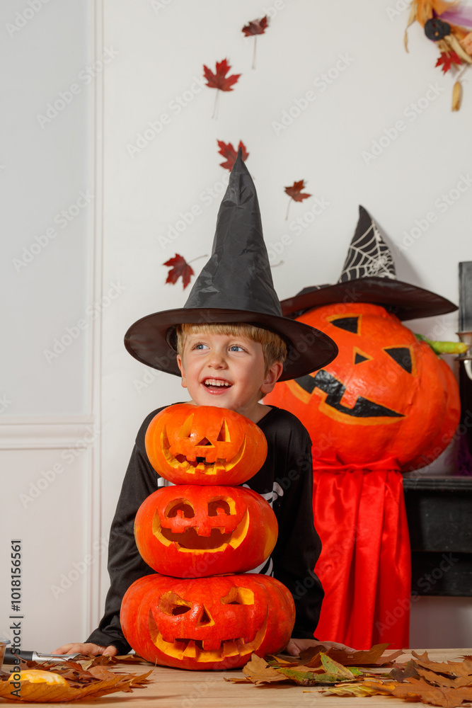 Fototapeta premium Boy with jack-o-lanterns and witch hat having Halloween fun