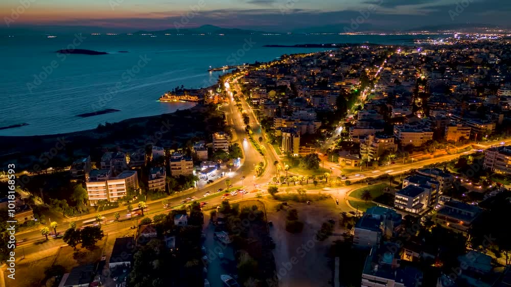 Aerial hyper lapse view of the Athens Riviera coastline with Voula suburb and Vouliagmenis street during dusk with traffic light trails, Greece