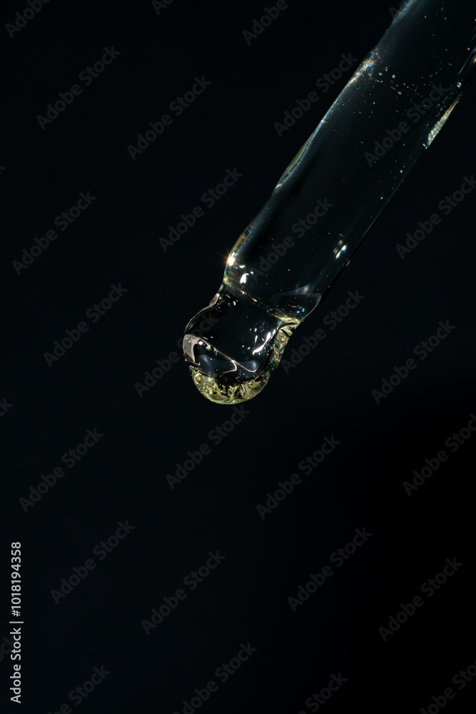 Bottle pipette dropper close up and Liquid retinol or vitamin c gel or serum on a black background.