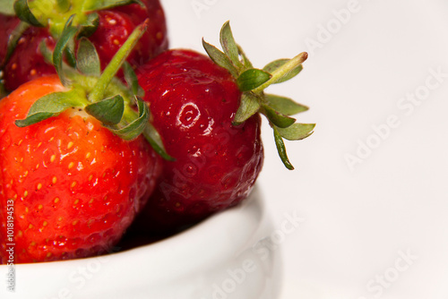 Fragment of strawberries in a white porcelain cup. The different textures can be appreciated