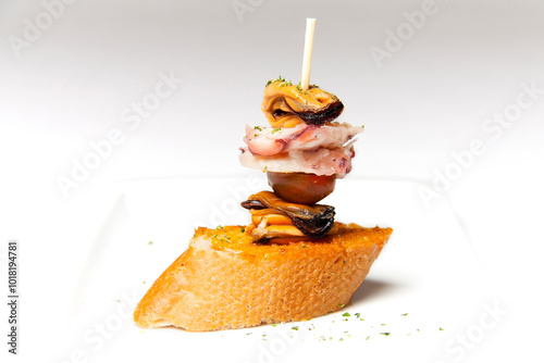 White plate of crispy bread skewer with portion of mussel, tomato and octopus on white background