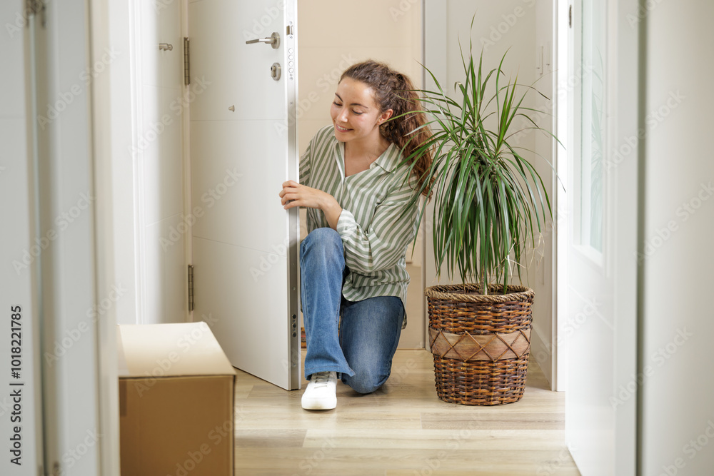 Young woman entering the door of her new house. She is a homeowner. New beginnings. New decor, plants. Moving with boxes. Mortgage concept, new tenant, paying rent. Young woman entering the door of her new house. She is a homeowner. New beginnings. New decor, plants. Moving with boxes. Mortgage concept, new tenant, paying rent.