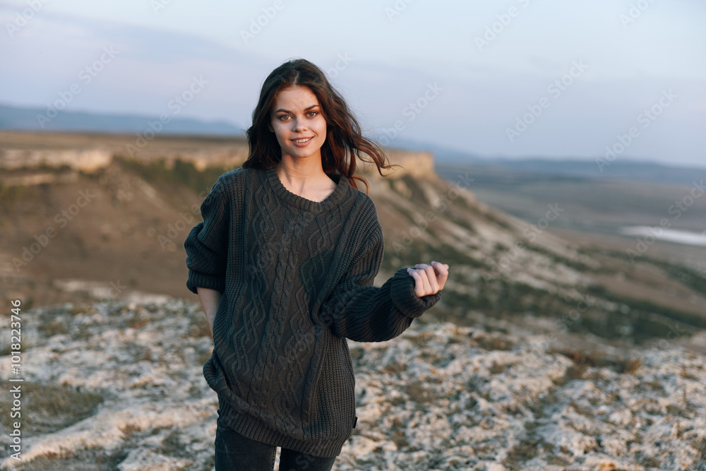 Woman in black sweater standing on hill with majestic mountain backdrop Woman in black sweater standing on hill with majestic mountain backdrop