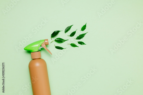 Bottle with cleaning spray on podium with green leaves on green background top view. Eco friendly home cleaning product, copy space