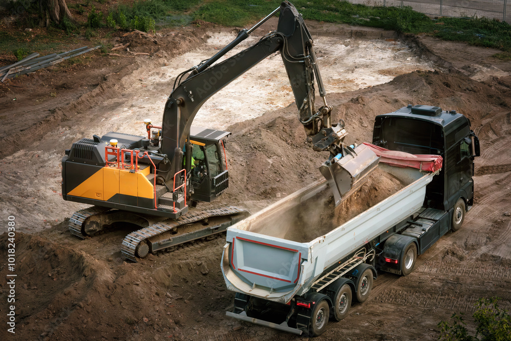 Excavator loading dirt into a truck, view from above