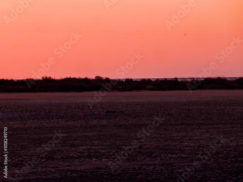 Red flush, Aurora. Dull sundown, stuffy air. Sunset over the saltpan lake after a sultry day, dull orange light due to the high humidity