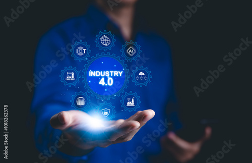 Smart industry 4.0 technology concept. A person holding digital interface with glowing icons representing Industry 4.0, IoT, AI, automation, and smart manufacturing technologies. Factory modern,