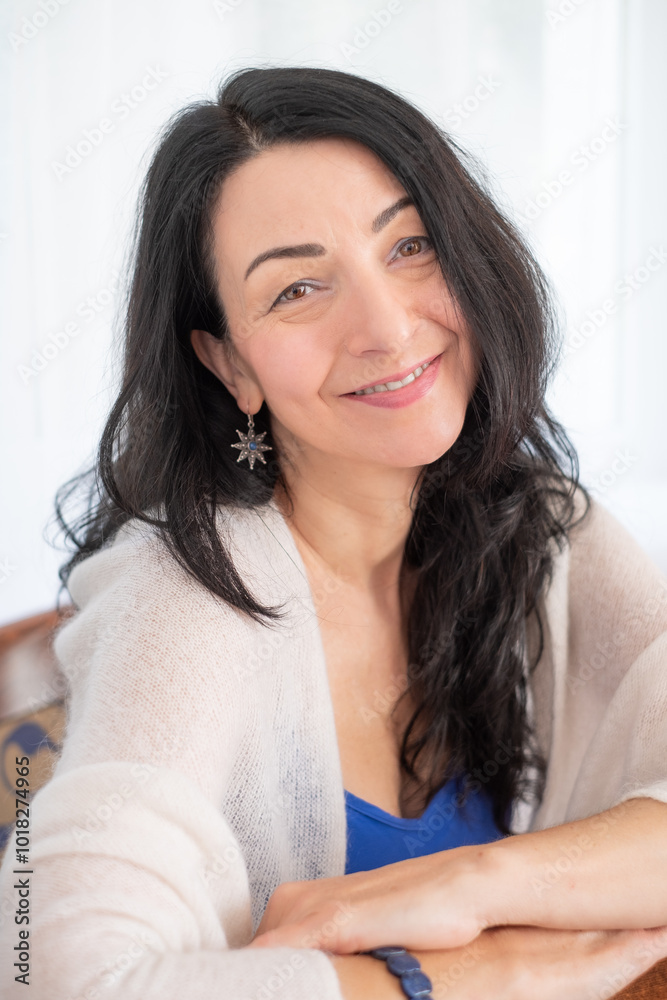 Smiling Woman with Long Hair Sitting on Chair in Bright Room with Natural Light, Relaxation Concept Smiling Woman with Long Hair Sitting on Chair in Bright Room with Natural Light, Relaxation Concept