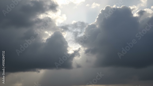 A moody sky with heavy gray clouds and soft sunlight peeking through, creating a dramatic contrast between light and shadow 