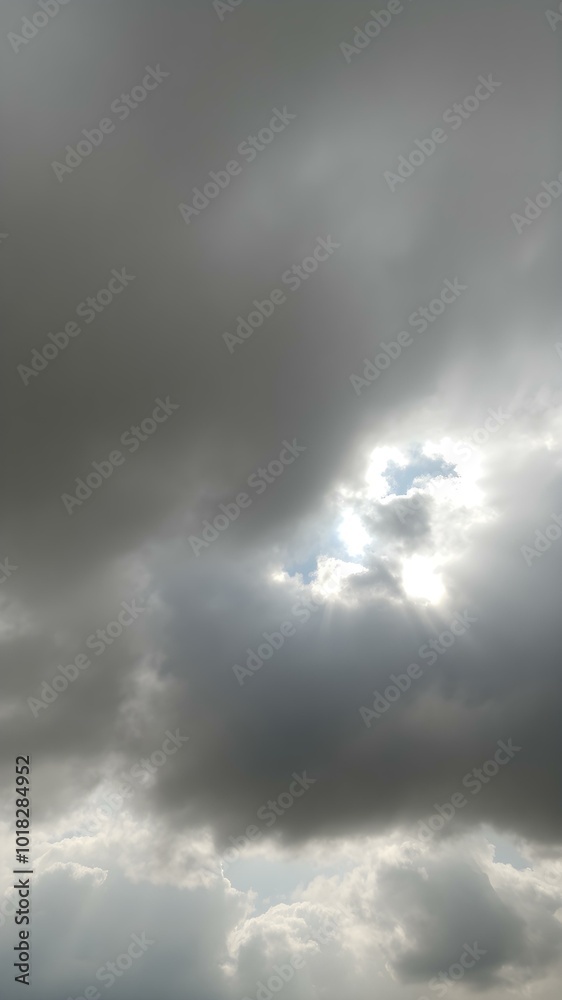 Obraz premium A moody sky with heavy gray clouds and soft sunlight peeking through, creating a dramatic contrast between light and shadow 