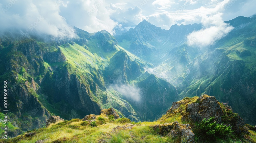 Obraz premium Majestic mountain range with cloudy sky and green hills.