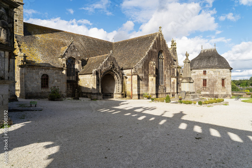 L'église et la chapelle funéraire de l'enclos paroissial de Sizun se dressent fièrement sous un ciel bleu, témoignant de l'architecture bretonne traditionnelle et du riche patrimoine historique local.