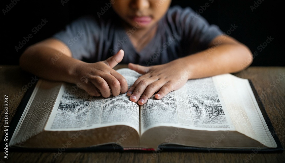 A child's small hand touching the center of an open Bible A child's small hand touching the center of an open Bible