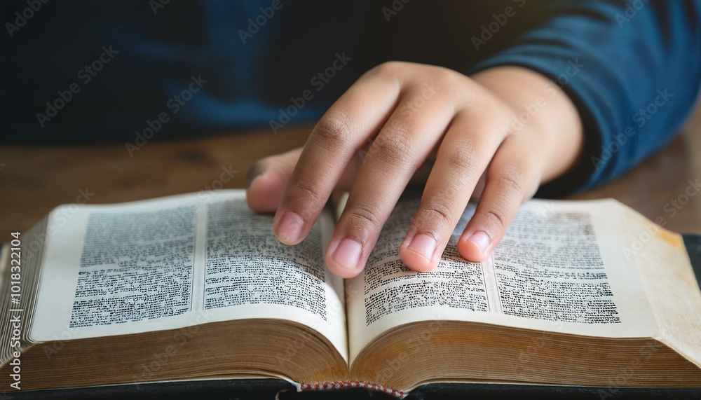Fototapeta premium A teenage hand resting on the Bible's pages