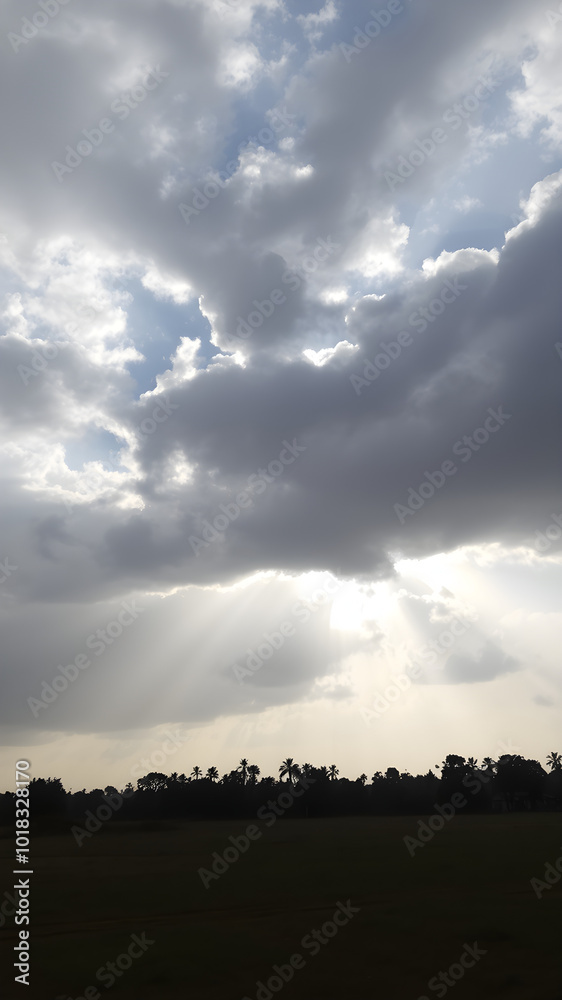 A cloudy day with the sun breaking through the clouds in a few places, creating bright sunbeams that illuminate patches of the ground A cloudy day with the sun breaking through the clouds in a few places, creating bright sunbeams that illuminate patches of the ground
